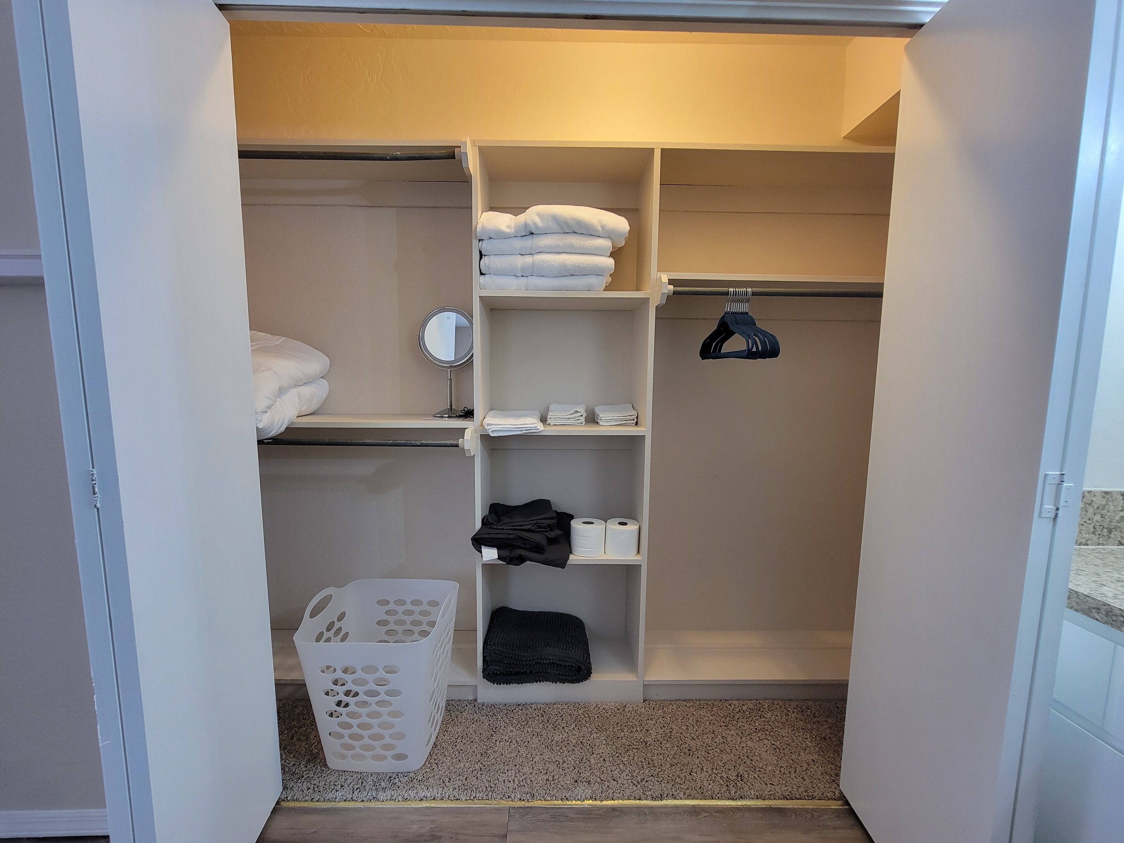 A neatly organized closet with shelves for folded clothes, a hanging rack, and a basket.