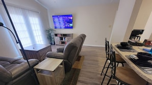 En moderne stue med sofa, sofabord og et fjernsyn hængt på væggen.