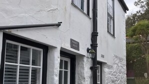 A white building with a sign reading "MARKET HOUSE" and a black door. - Cottage - Sleeps 4 - Fireplace - Internet (Penzance)