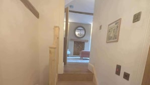 Een trap die leidt naar een kamer met een open haard, een ronde spiegel en een lijst met een afbeelding.