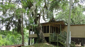 Une cabane rustique dotée d’une terrasse en bois et d’un escalier menant à un porche.
