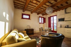 Una sala de estar acogedora con un sofá, una mesa de comedor y sillas. Hay una zona de cocina con armarios y un microondas.