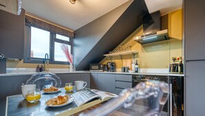 Une cuisine moderne avec un coin repas, comprenant un buffet pour le petit-déjeuner avec des croissants, du jus d’orange et une tasse de café.