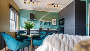 Une cuisine moderne avec des chaises de couleur turquoise, une table à manger et une grande fenêtre.