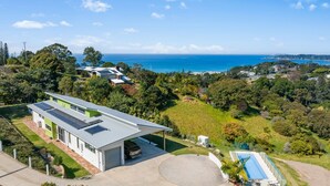 A modern house with solar panels, a swimming pool, and a view of the ocean. - Ciao Korora - The Ultimate Coffs Coast Getaway (Korora)
