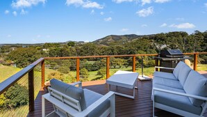 A deck with outdoor furniture, a grill, and a view of a hilly landscape. - Ciao Korora - The Ultimate Coffs Coast Getaway (Korora)