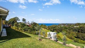 A residential property with a view of the ocean, lush greenery, and a well-maintained lawn. - Ciao Korora - The Classic (Korora)