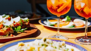 A dining table with a variety of dishes and two glasses of a red beverage. - Ciao Korora - The Classic (Korora)