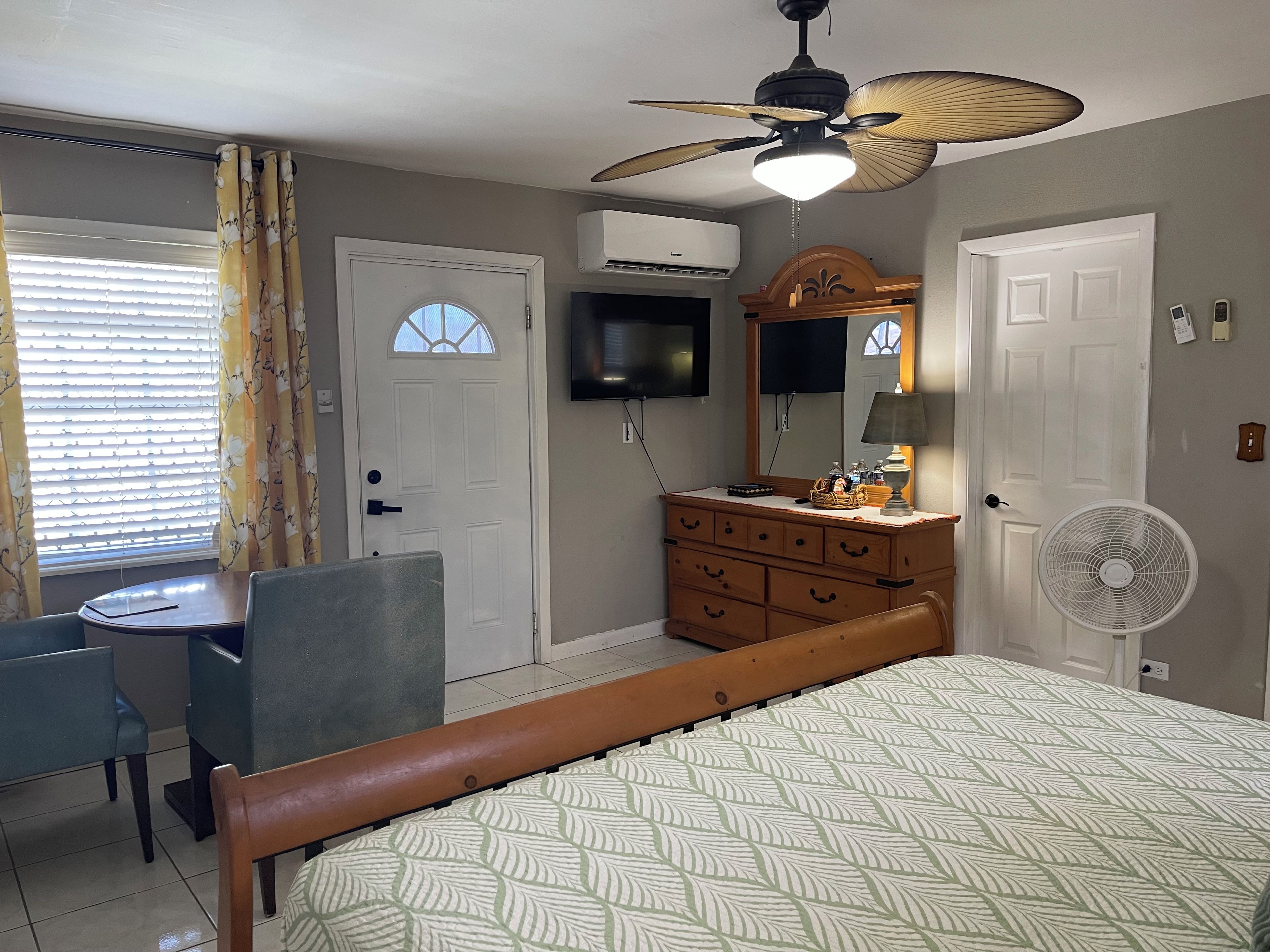 Une chambre à coucher comprenant un lit, une commode, un téléviseur et un ventilateur de plafond.