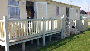 A mobile home with an open door, a white porch, and a staircase leading to the entrance. - 3bed-sleeps6-pet Friendly-familyfriendly (Mablethorpe)