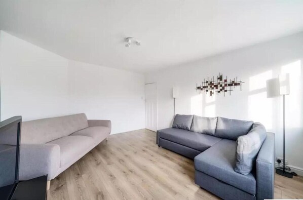 A modern living room with two sofas, a floor lamp, and a wall art piece.