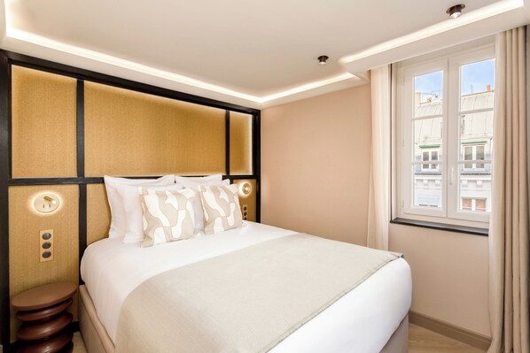 A neatly arranged hotel room with a bed, bedside tables, and a window with curtains.