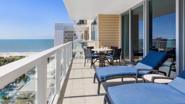 Un balcon donnant sur la plage, aménagé avec des chaises longues et une table.