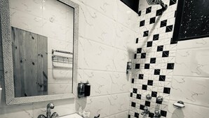 Une salle de bain avec un lavabo blanc, des carreaux noirs et blancs disposés en motif à damier, un miroir et un espace douche.