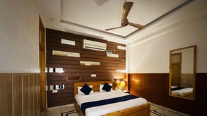 Une chambre moderne avec un lit en bois, un ventilateur de plafond et un climatiseur fixé au mur.