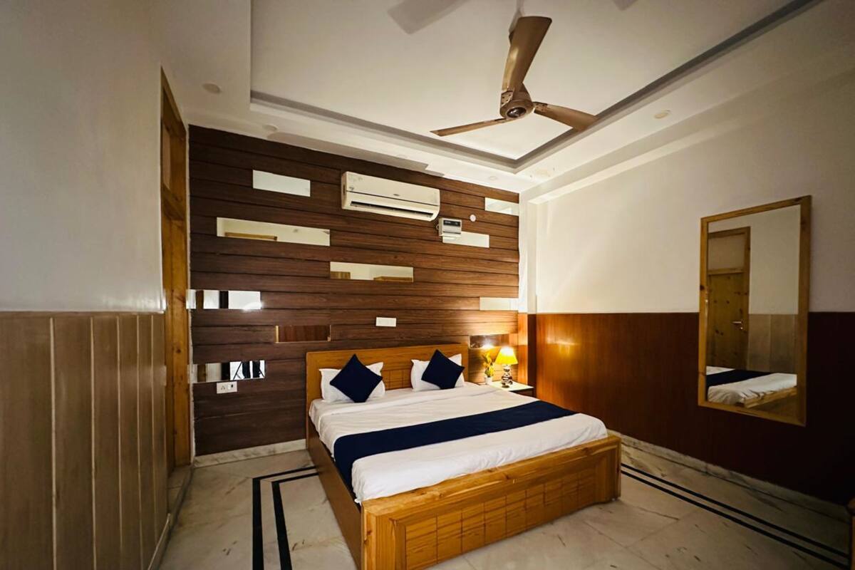 Quarto moderno com cama de madeira, ventilador de teto e ar condicionado fixado na parede.