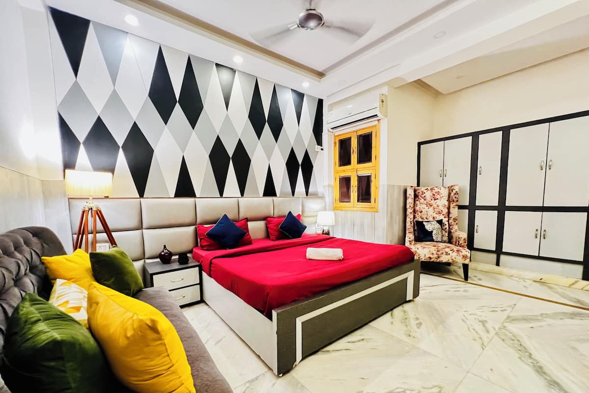 Quarto com cama, mesas de cabeceira, sofá, guarda-roupa e decoração na parede.