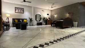 Un salon spacieux avec un grand canapé, un grand miroir rond et un lit doté d’une tête de lit.