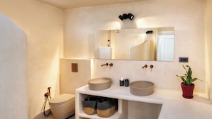 A modern bathroom with a large mirror, two sinks, a toilet, and a potted plant.