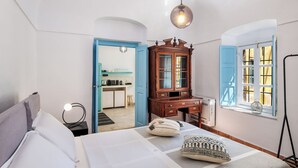 A bedroom with a bed, a wooden cabinet, a desk, and a window with curtains.