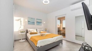 A modern bedroom with a bed, bedside tables, and artwork on the wall. - Villa Poco Loco -Comfort Two Bedroom Apartment (Dubrovačko-neretvanska županija)