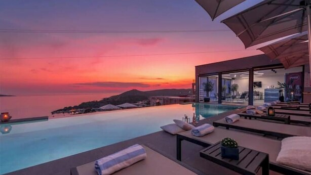A poolside lounge area with sun loungers and umbrellas, overlooking a body of water at sunset. - Villa Poco Loco - Deluxe Apartment with Sea View (Dubrovacko-neretvanska županija)