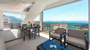 A modern living room with a balcony, a dining area, and a view of the sea. - Villa Poco Loco - Deluxe Apartment with Sea View (Dubrovacko-neretvanska županija)