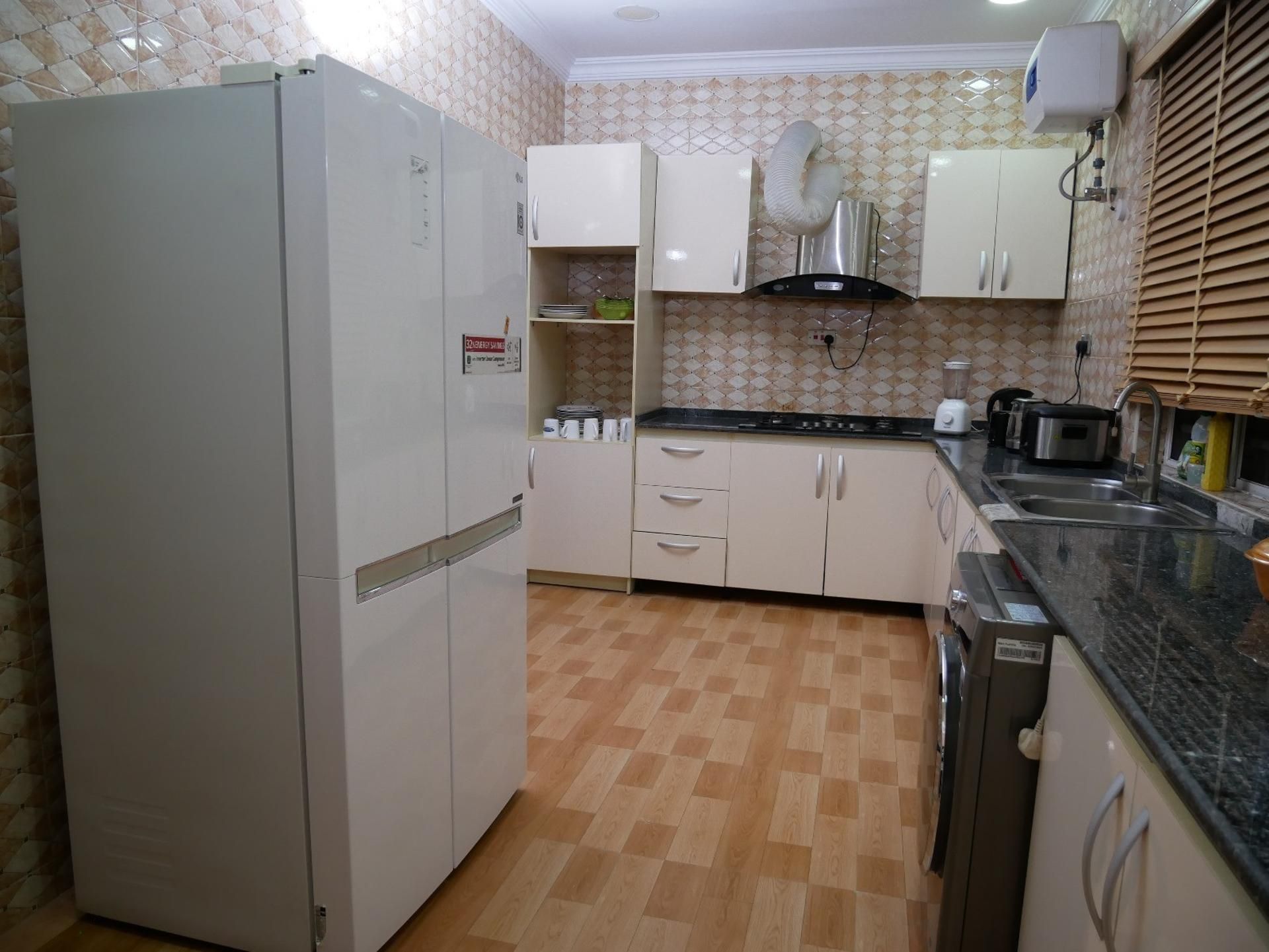Een keuken met een koelkast, kastjes, een fornuis en een spoelbak.