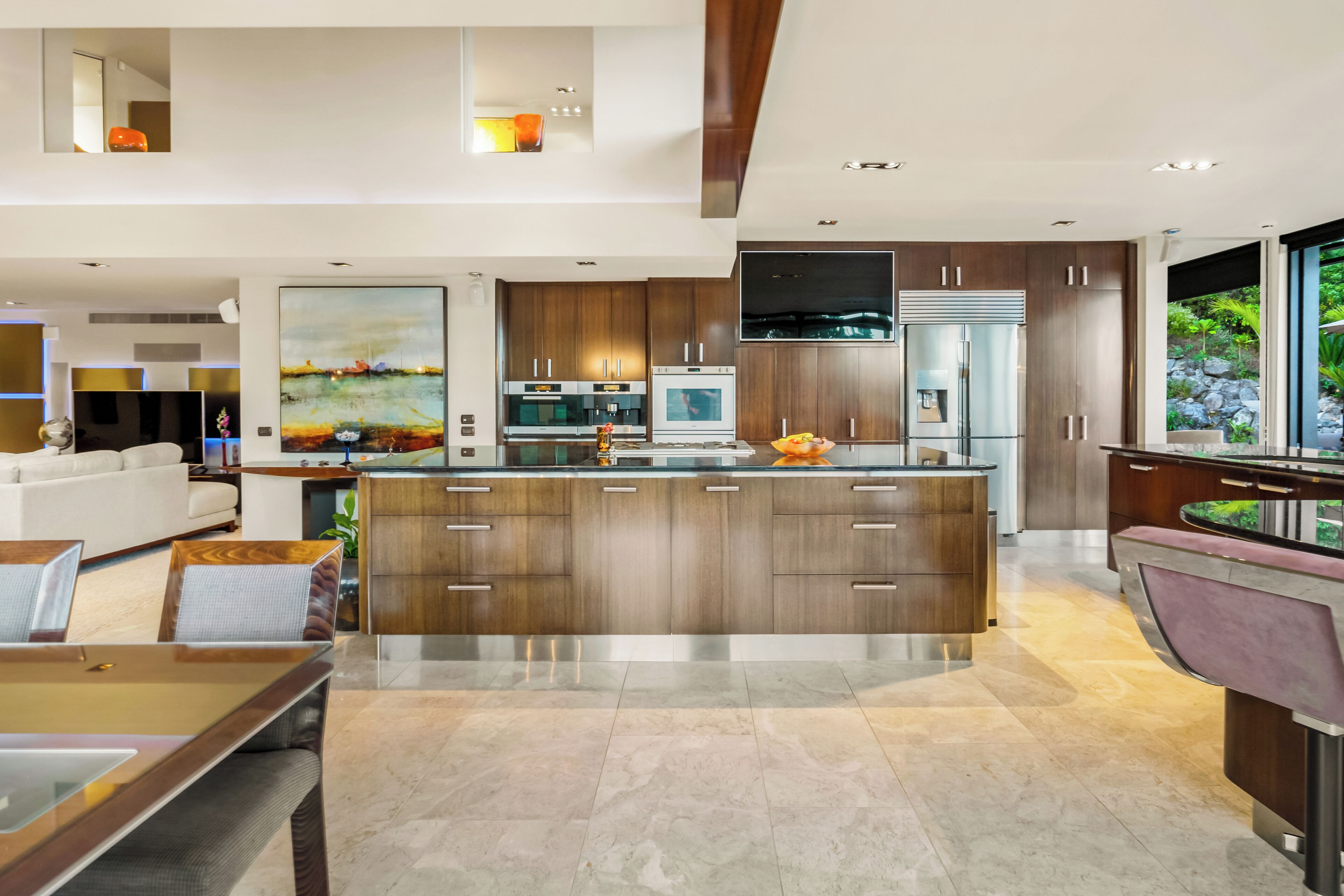 A modern kitchen with a large island, wooden cabinets, and stainless steel appliances.
