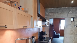 A kitchen with a stainless steel sink, a coffee maker, and wooden cabinets. - Large apartment in village center with direct access to ski and hiking trails (Prémanon)