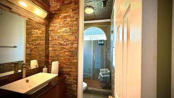 A bathroom with a stone wall, a sink, and a shower area.