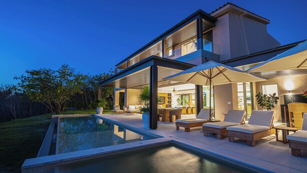 Une maison moderne dotée d’une piscine, d’un espace extérieur aménagé et d’un intérieur bien éclairé.
