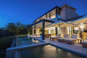 Une maison moderne dotée d’une piscine, d’un espace extérieur aménagé et d’un intérieur bien éclairé.