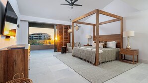 Une chambre moderne avec un lit à baldaquin, un téléviseur à écran plat et une vue sur le coucher de soleil, visible à travers une grande fenêtre.