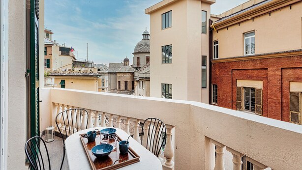 A balcony with a table set for two, overlooking a cityscape with historic buildings. - Brignole de Ferrari Refined Home by Wonderful Italy (Genoa)
