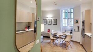 A modern kitchen with a dining area, featuring a round table with chairs, a large mirror, and framed artwork on the wall. - Brignole de Ferrari Refined Home by Wonderful Italy (Genoa)