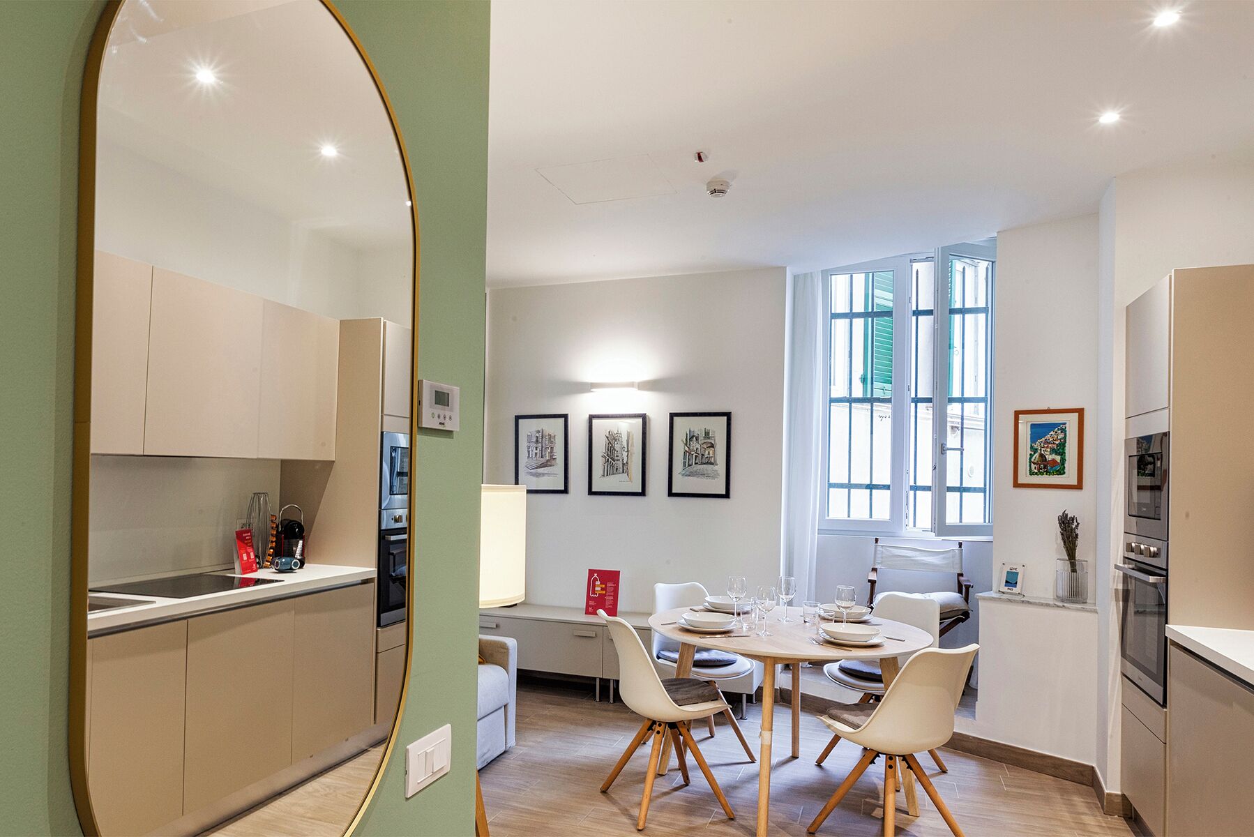 Une cuisine moderne dotée d’appareils électroménagers intégrés, un coin repas avec une table ronde et des chaises, et des œuvres d’art accrochées aux murs.