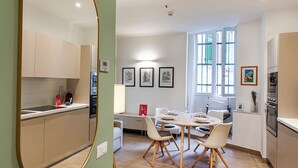 A modern kitchen with built-in appliances, a dining area with a round table and chairs, and artwork on the walls. - Brignole de Ferrari Refined Home by Wonderful Italy (Genoa)