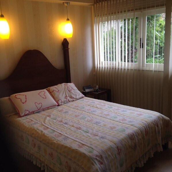 A bedroom with a wooden headboard, a floral bedspread, and two bedside lamps.