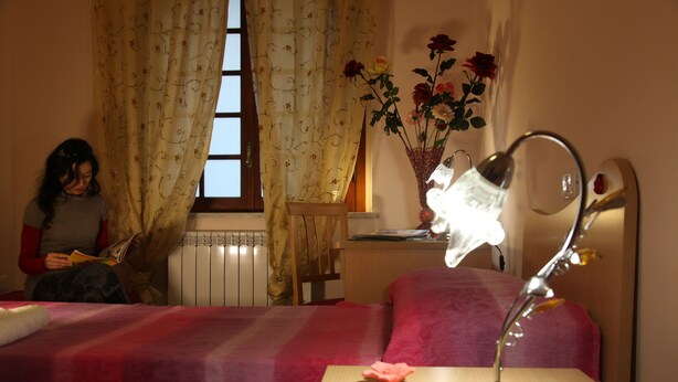 A room with a bed, a bedside table with a lamp, a window with curtains, and a vase with flowers. - Cozy mini-apartment ideal for a couple. (Tropea)