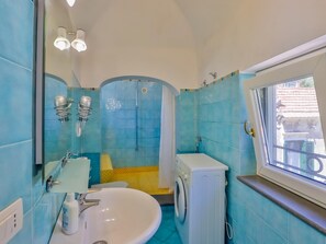 Ein Badezimmer mit Waschbecken, Spiegel, Dusche und einem Fenster.