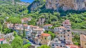 A coastal village with traditional Mediterranean architecture, narrow streets, and lush greenery.