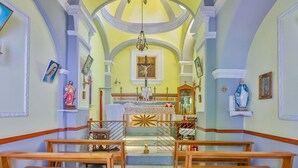 A church interior with wooden pews, a central altar, and religious statues.