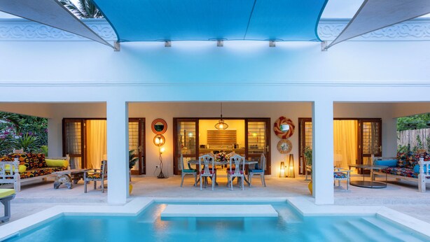 Zona de piscina con mobiliario para comer, un espacio de descanso cubierto y vistas a la piscina.