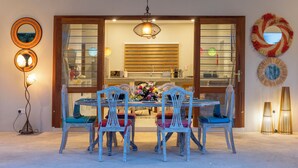 Un comedor con una mesa de madera y seis sillas, una araña y espejos decorativos en la pared.