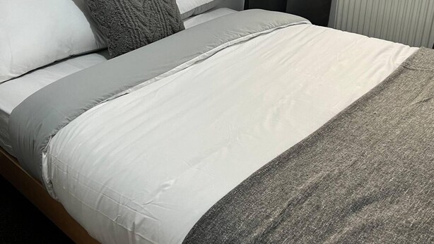 A neatly made bed with a wooden headboard, white bedding, and a gray throw blanket. - 3bedroom- Near to Station-private Garden-wifi (Liverpool)
