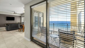 Ein modernes Wohnzimmer mit Flachbildfernseher, Essbereich und einem Balkon mit Meerblick.