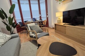 Ein modernes Wohnzimmer mit Sofa, Sesseln und einem Fernseher auf einer Holzkommode.