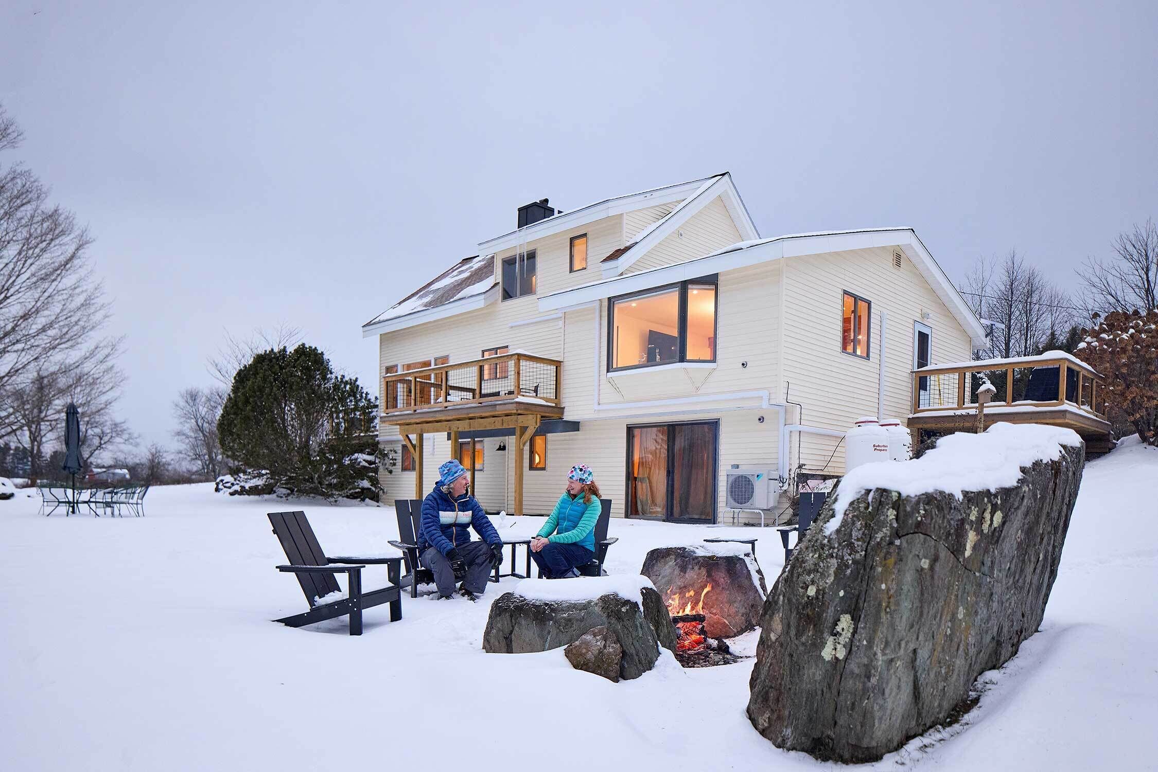 A two-story house with a covered patio and a fire pit.