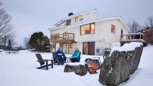 Et toetagers hus med en overdækket terrasse og et bålsted.